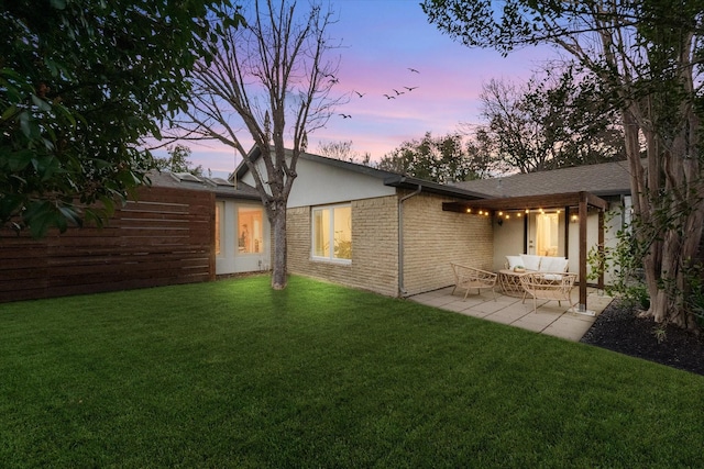 back of property at dusk with a patio area, brick siding, a lawn, and outdoor lounge area