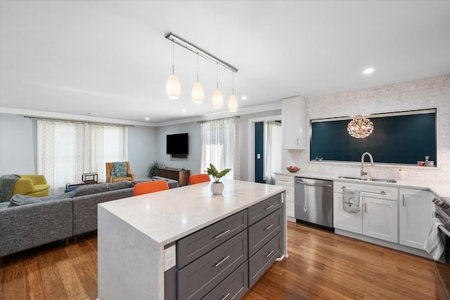 kitchen with stainless steel appliances, wood finished floors, a sink, white cabinets, and open floor plan