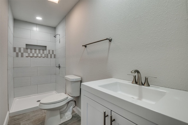 full bath featuring a textured wall, toilet, vanity, and a shower stall