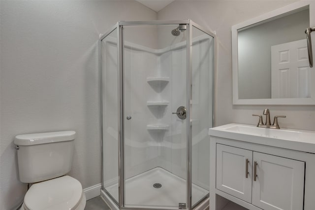 bathroom with vanity, a shower stall, and toilet