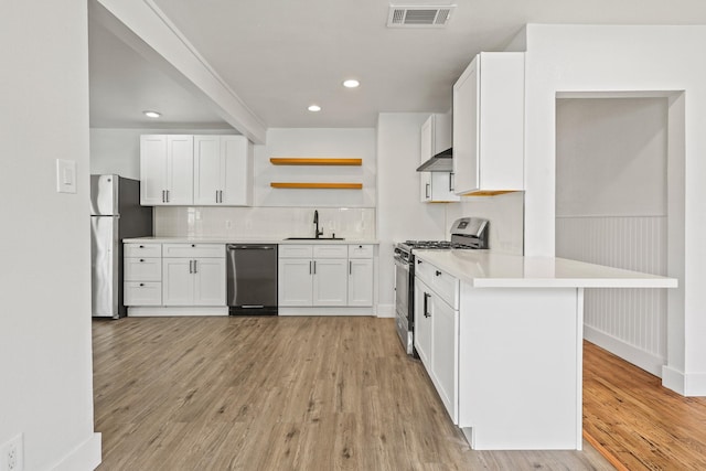 kitchen with light wood finished floors, open shelves, visible vents, appliances with stainless steel finishes, and wall chimney range hood