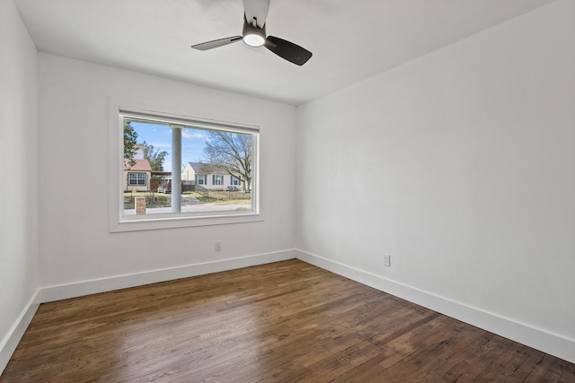 spare room with dark wood-style floors, baseboards, and a ceiling fan