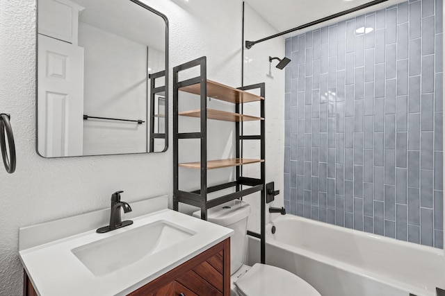 bathroom featuring a textured wall, shower / bathing tub combination, vanity, and toilet