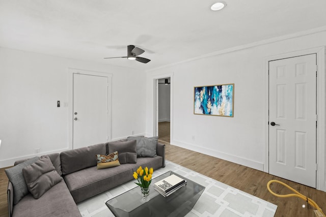 living room with ceiling fan, baseboards, and wood finished floors