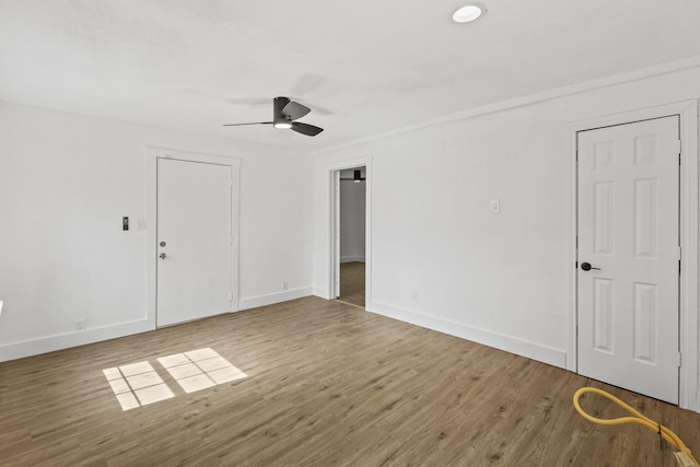 empty room featuring wood finished floors, a ceiling fan, and baseboards