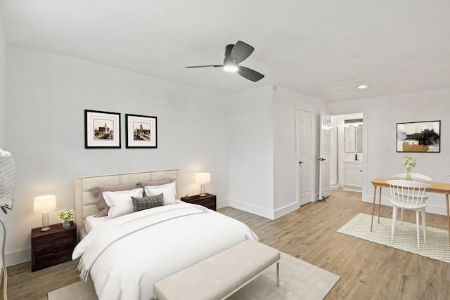 bedroom featuring a ceiling fan, ensuite bath, light wood-style flooring, and baseboards