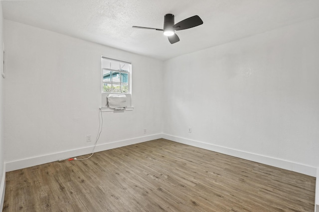 empty room featuring ceiling fan, a textured ceiling, baseboards, and wood finished floors