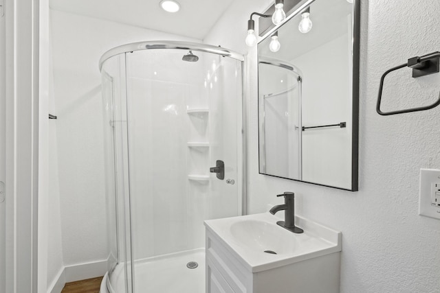 bathroom with a stall shower, a textured wall, wood finished floors, and vanity