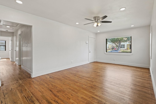 empty room featuring baseboards, wood finished floors, attic access, and recessed lighting