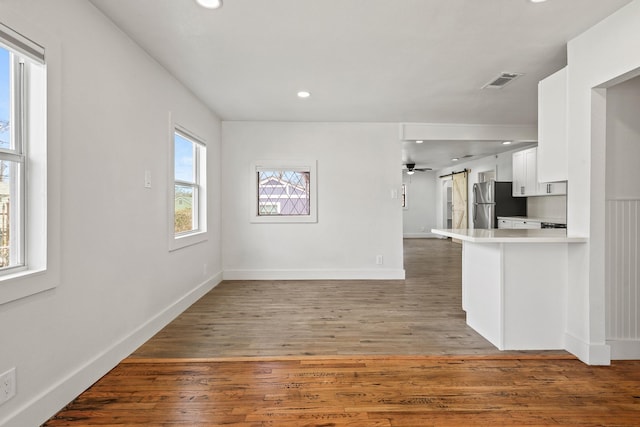 kitchen with a barn door, visible vents, light wood-style flooring, freestanding refrigerator, and white cabinetry