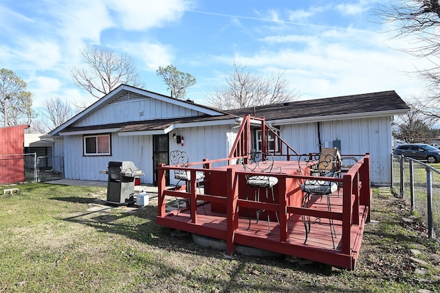 back of property with roof with shingles, fence, a lawn, and a wooden deck