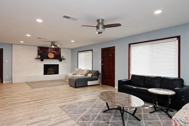 living room featuring a fireplace, recessed lighting, visible vents, light wood-style floors, and a ceiling fan