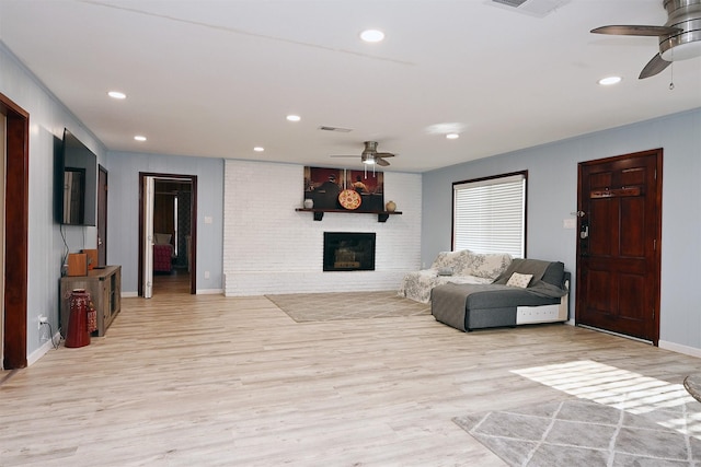 living area featuring ceiling fan, light wood-style flooring, recessed lighting, visible vents, and a brick fireplace