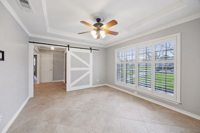 spare room featuring a barn door, visible vents, baseboards, a raised ceiling, and crown molding