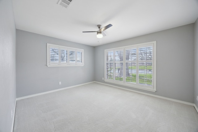 carpeted empty room featuring baseboards, visible vents, and ceiling fan