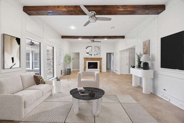 living room featuring beam ceiling, a fireplace, light tile patterned floors, a decorative wall, and a ceiling fan