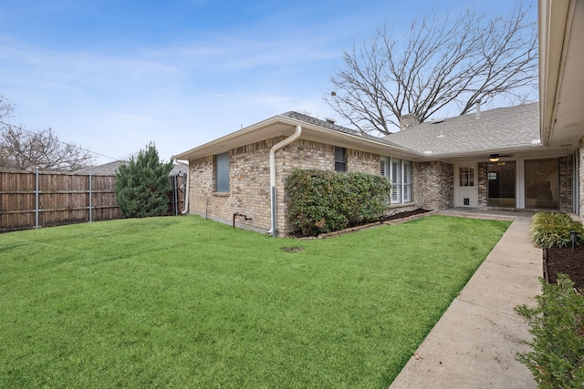 view of home's exterior with fence private yard, a chimney, a lawn, and brick siding