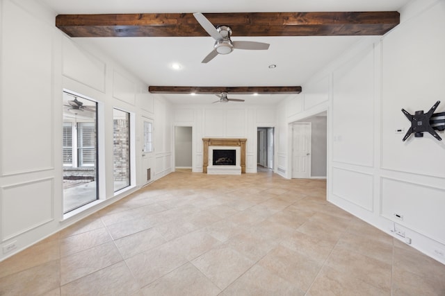 unfurnished living room with a fireplace, a decorative wall, and beam ceiling