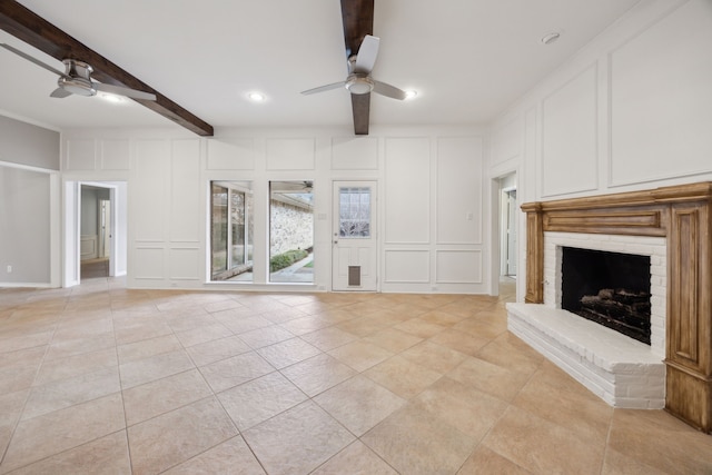 unfurnished living room featuring ceiling fan, beam ceiling, and a decorative wall