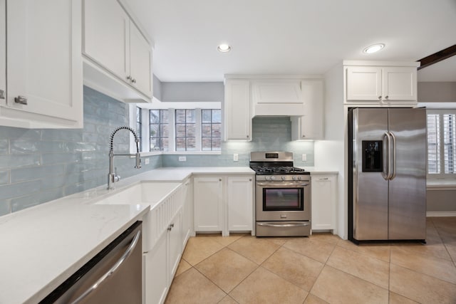 kitchen with stainless steel appliances, custom exhaust hood, a sink, and white cabinets