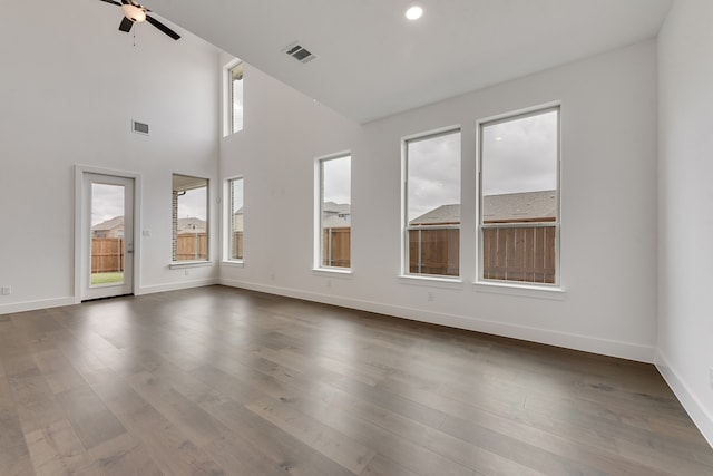 empty room with dark wood-type flooring, visible vents, and baseboards