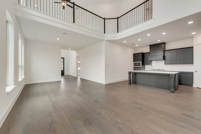 kitchen with dark wood-type flooring, open floor plan, light countertops, and a center island with sink