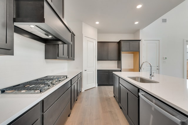 1517 Kinglet Pl, Celina, TX 75009 - kitchen featuring appliances with stainless steel finishes, wall chimney exhaust hood, a sink, light wood finished floors, and light countertops