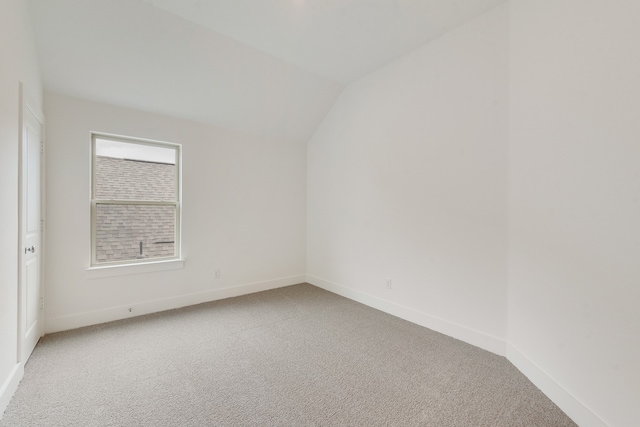 carpeted empty room with lofted ceiling and baseboards