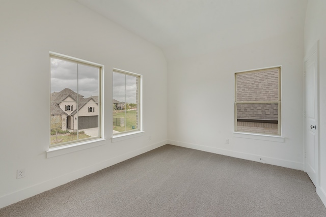 carpeted empty room featuring lofted ceiling and baseboards