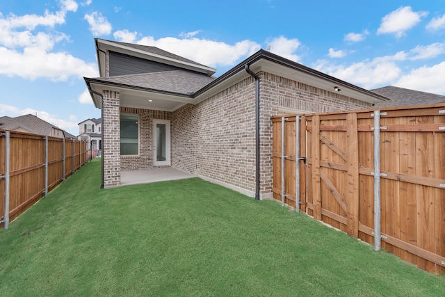 back of property featuring a lawn, a fenced backyard, a gate, a patio area, and brick siding