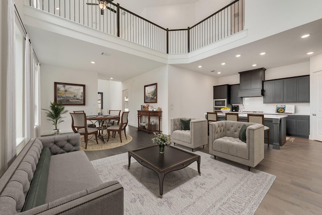 living room with light wood-style floors, recessed lighting, visible vents, and a high ceiling