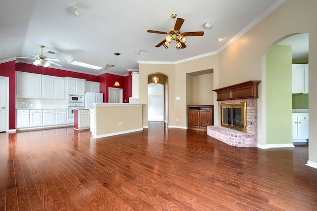 unfurnished living room with ornamental molding, a fireplace, ceiling fan, and wood finished floors