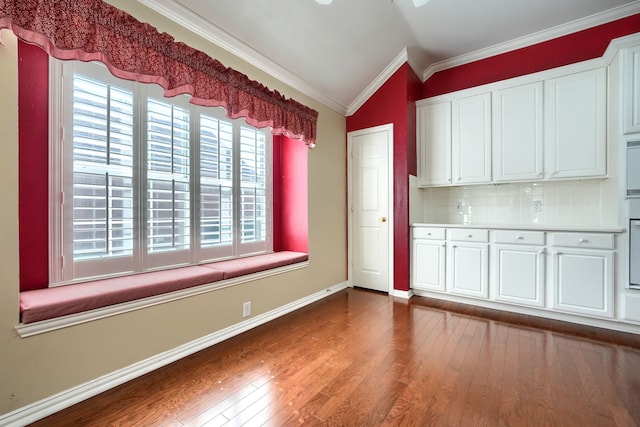 kitchen with dark wood finished floors, vaulted ceiling, crown molding, light countertops, and white cabinetry