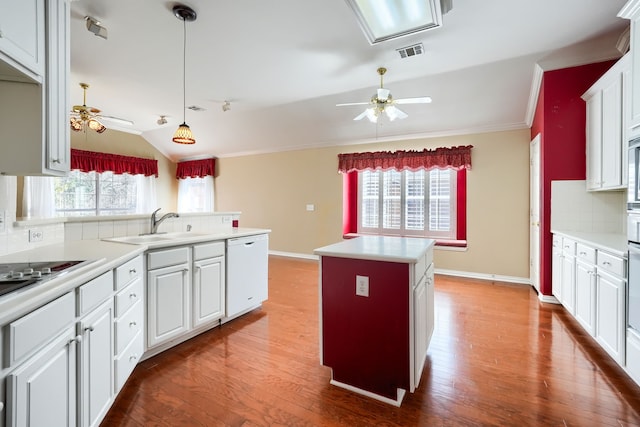 kitchen featuring a kitchen island, light countertops, white dishwasher, and visible vents