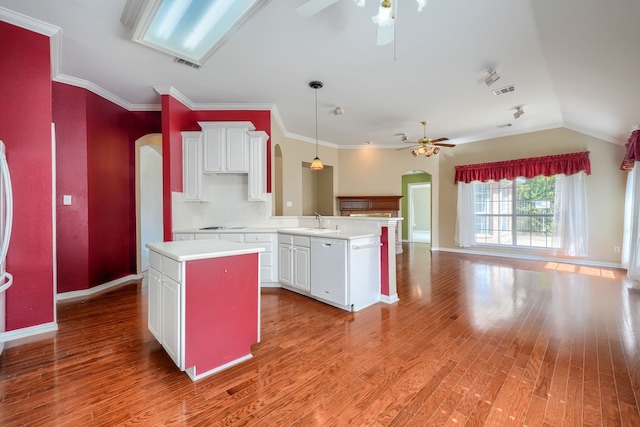 kitchen featuring arched walkways, open floor plan, a center island, a peninsula, and light countertops