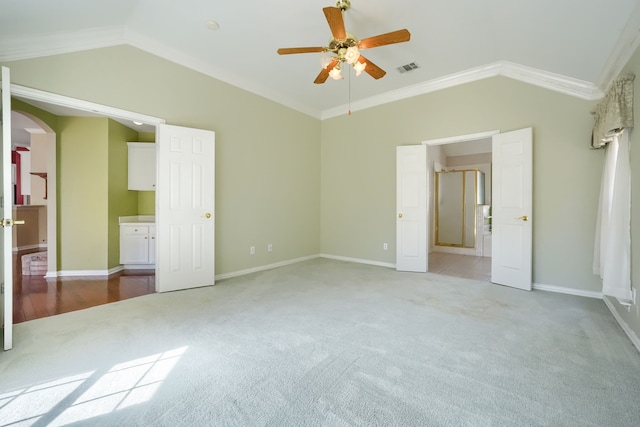 unfurnished bedroom featuring arched walkways, crown molding, light colored carpet, visible vents, and vaulted ceiling