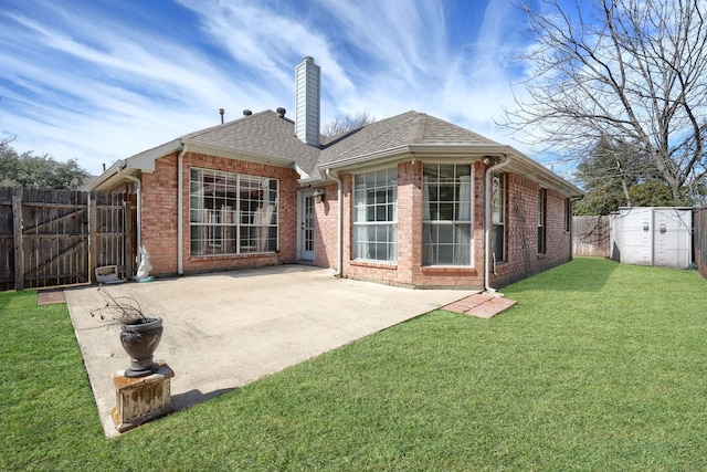 back of property with a lawn, a chimney, roof with shingles, a patio area, and brick siding