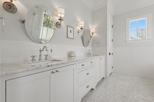 full bath featuring crown molding, a sink, tile walls, and double vanity