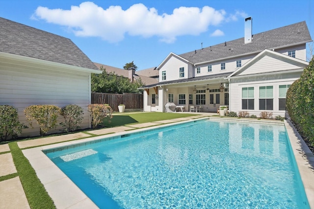 view of swimming pool featuring ceiling fan, a fenced backyard, a yard, a fenced in pool, and a patio area