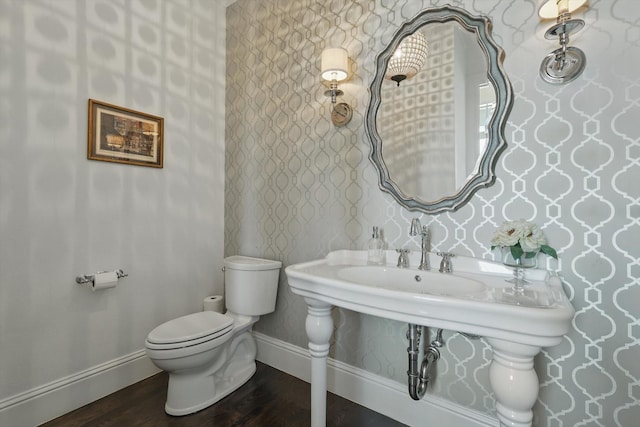 bathroom featuring wallpapered walls, toilet, baseboards, and wood finished floors