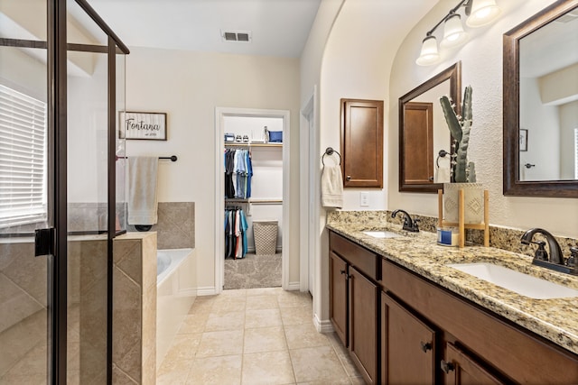 full bath featuring tile patterned flooring, a sink, visible vents, and a walk in closet