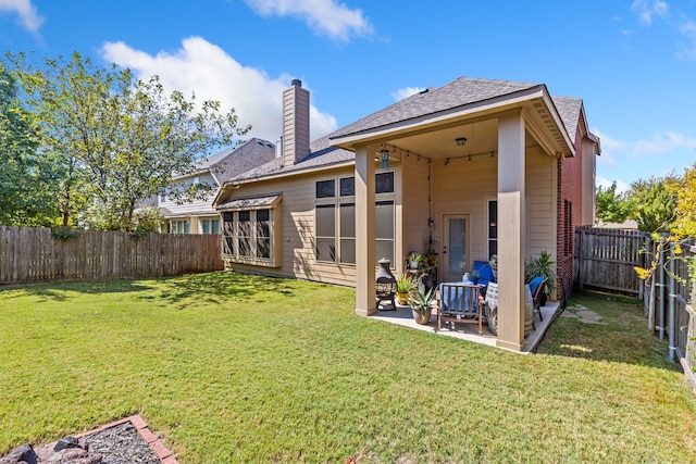 back of property featuring a fenced backyard, a lawn, a chimney, and a patio