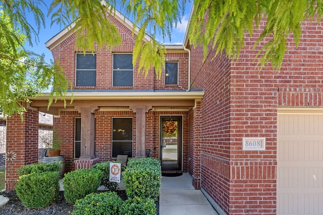 view of front of property featuring a garage, covered porch, and brick siding