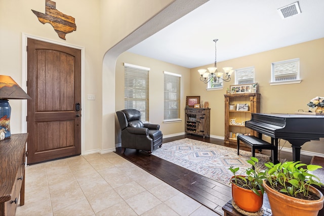 foyer entrance featuring an inviting chandelier, visible vents, baseboards, and light tile patterned flooring