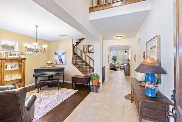 entrance foyer featuring arched walkways, visible vents, stairway, a chandelier, and baseboards