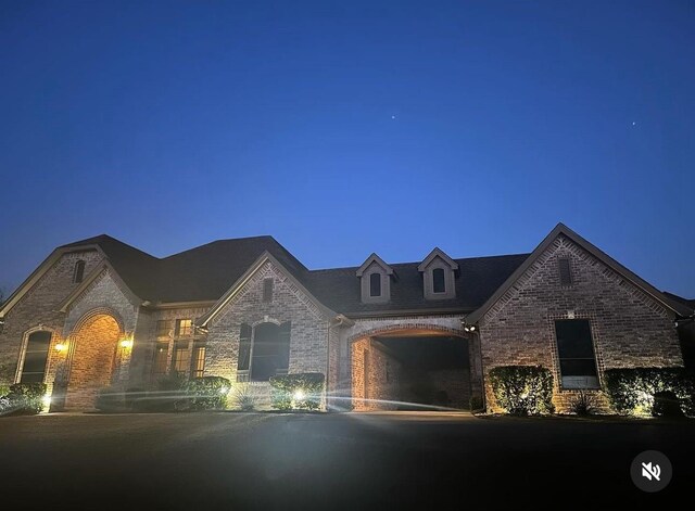 french country home featuring driveway and brick siding