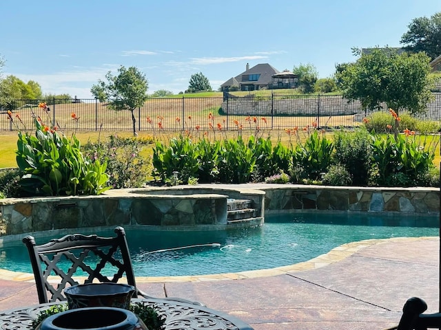 view of pool featuring a pool with connected hot tub and fence