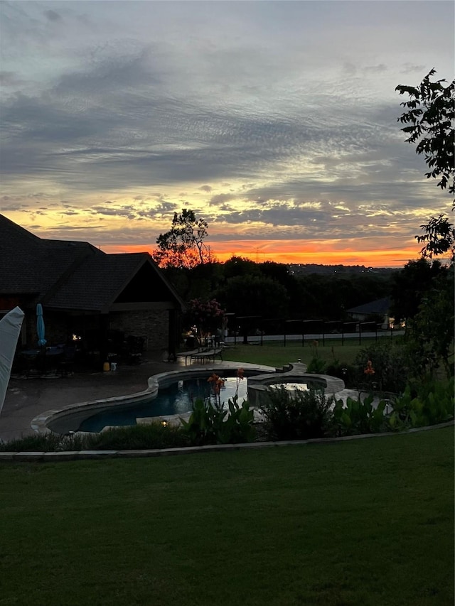 pool at dusk featuring fence, an outdoor pool, a patio, and a yard