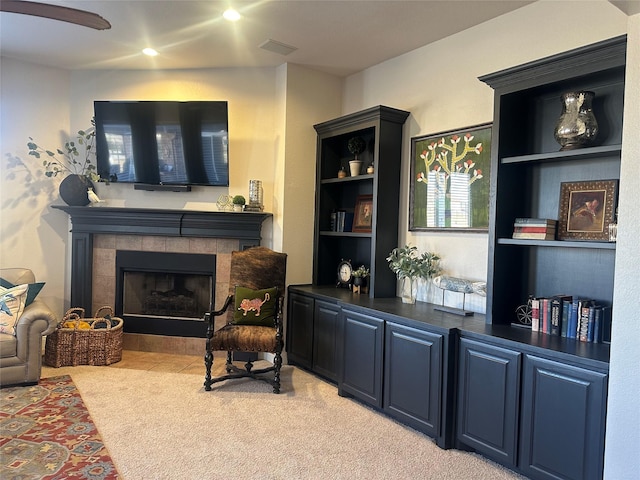 sitting room featuring a tile fireplace, visible vents, and light colored carpet