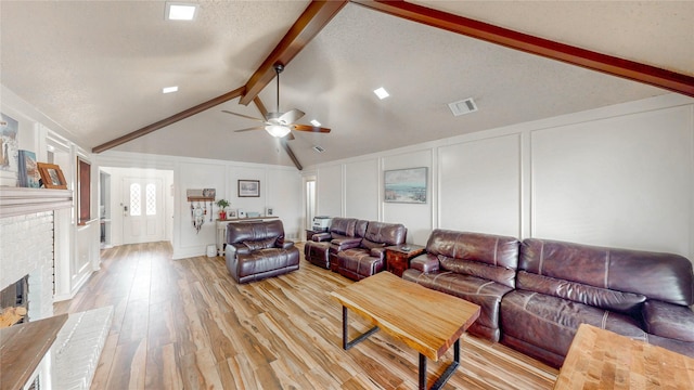 living room with lofted ceiling with beams, light wood finished floors, visible vents, and a decorative wall